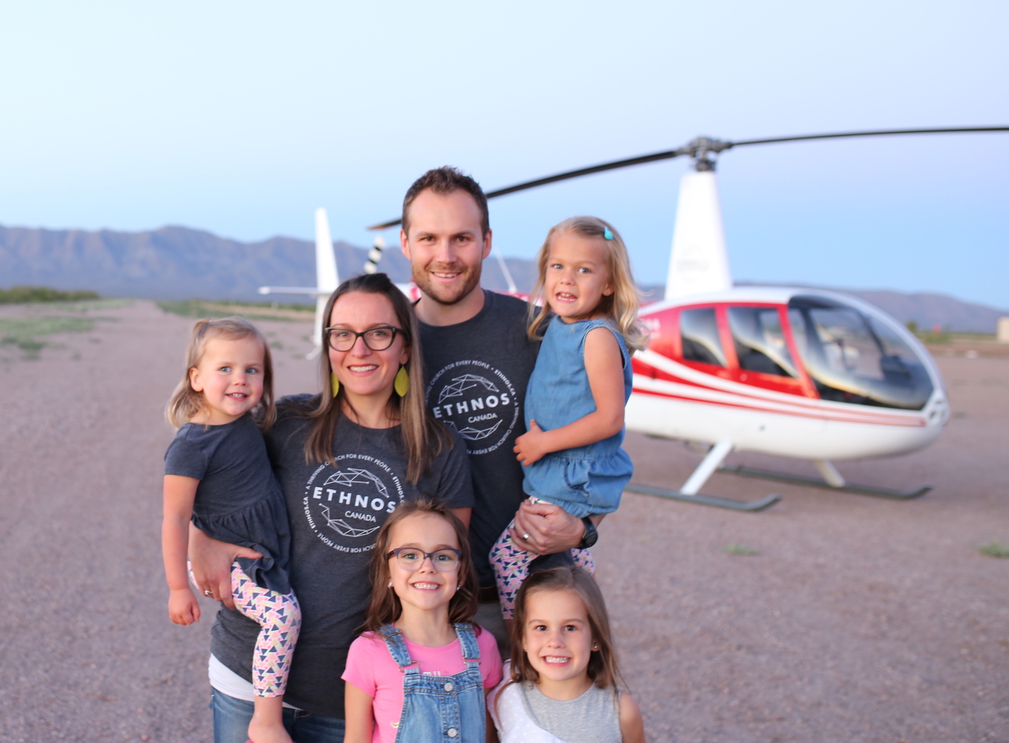 man and woman with their 4 daughters in Arizona with a helicopter in the background